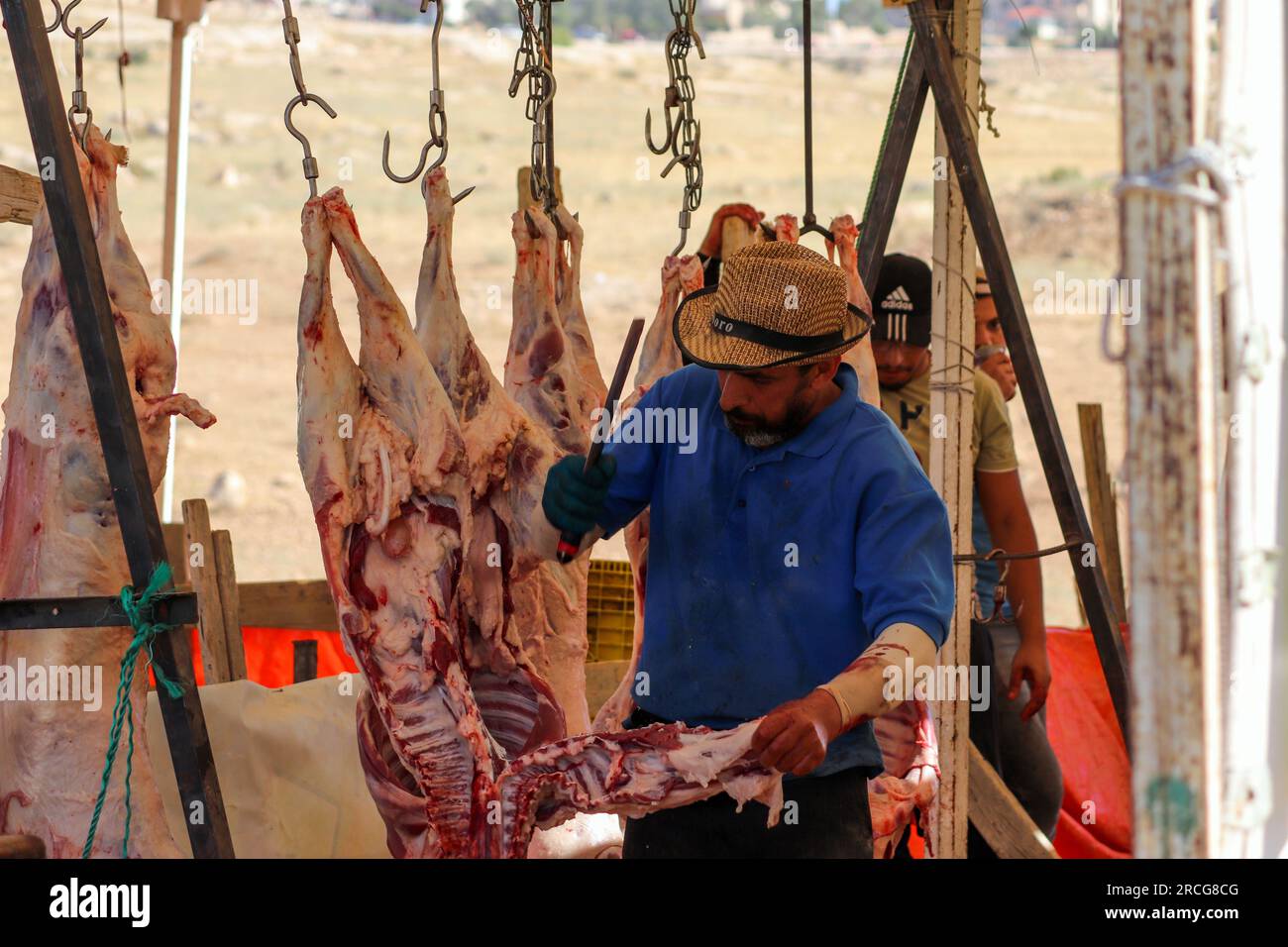 Ein Schweißer, ein Metzger schneidet das Fleisch eines geschlachteten Schafes in Aram und muslimischen Ländern während Eid al-Adha Al-Mubarak - Amman, Jordanien Stockfoto