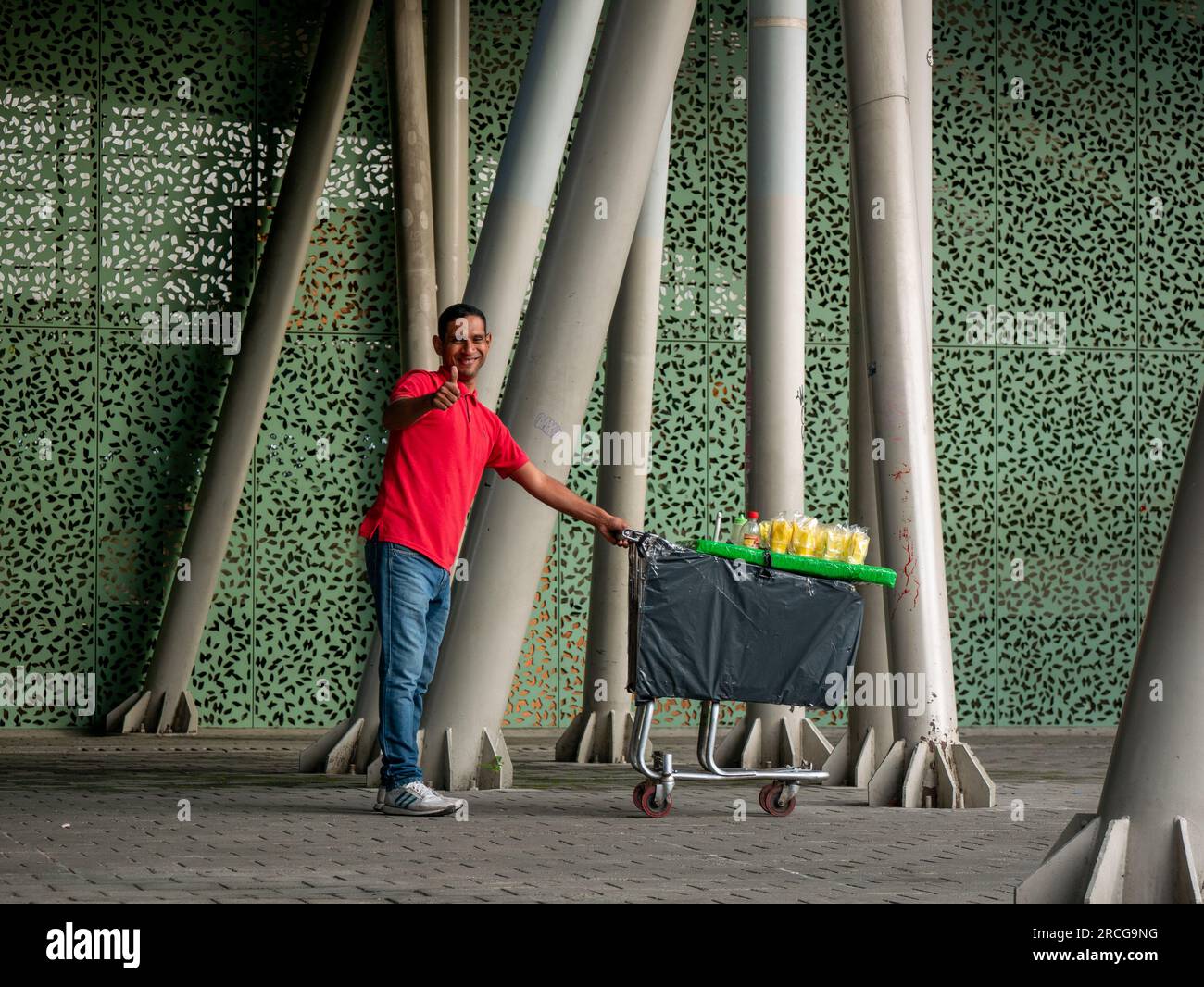 Medellin, Antioquia, Kolumbien - 3 2022. Juni: Kolumbianischer Mann, der Mangos in einem Wagen verkauft und der Kamera zuwinkt Stockfoto