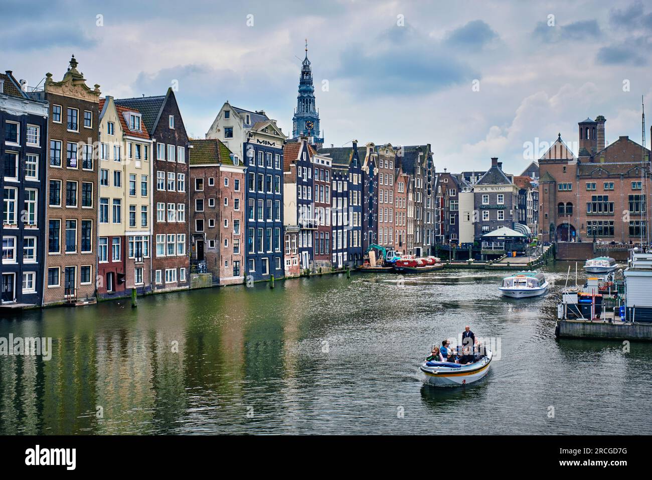 Grachtenfahrt mit Touristenboot in Amsterdam am Damrak Kanal und Pier Stockfoto