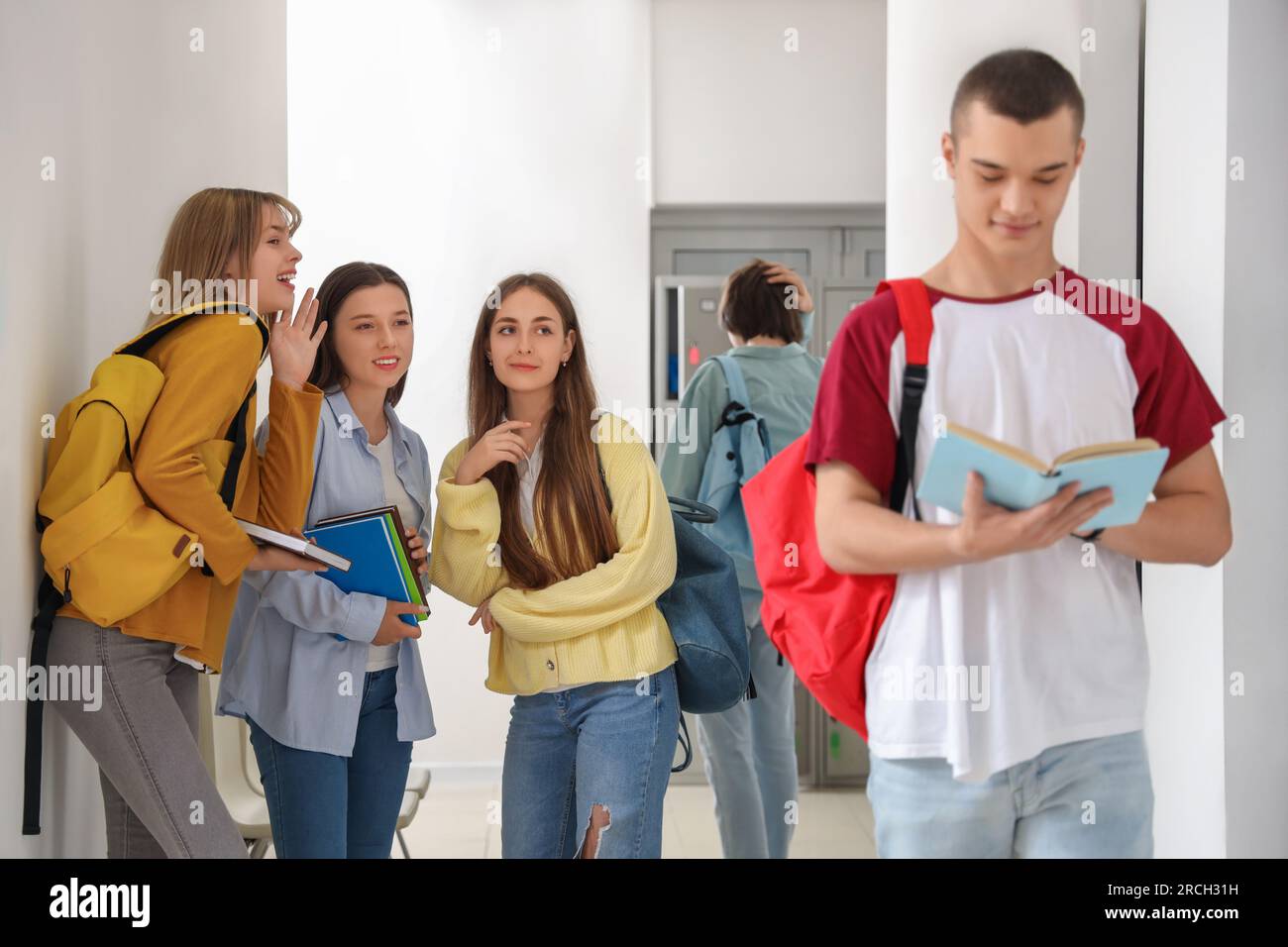 Teenager-Mädchen, die in der Schule über Klassenkameraden reden Stockfoto