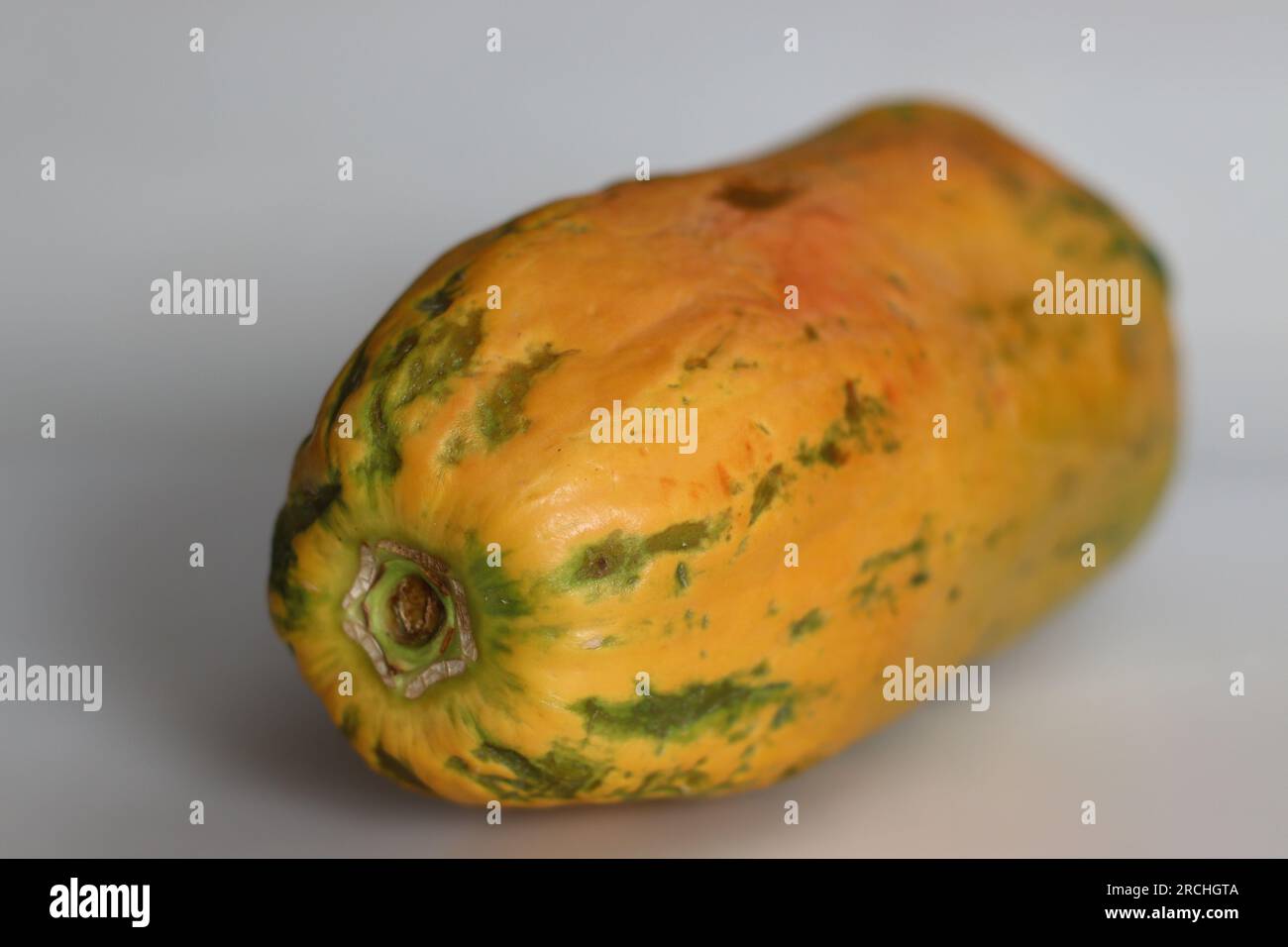 Reif und verzehrfertig. Lange reife Papaya mit orangisch-gelber Haut und weich zu berühren. Aufnahme auf weißem Hintergrund Stockfoto