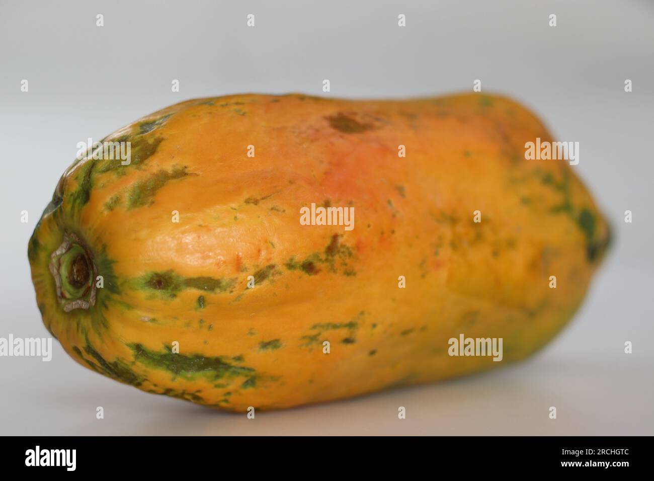 Reif und verzehrfertig. Lange reife Papaya mit orangisch-gelber Haut und weich zu berühren. Aufnahme auf weißem Hintergrund Stockfoto