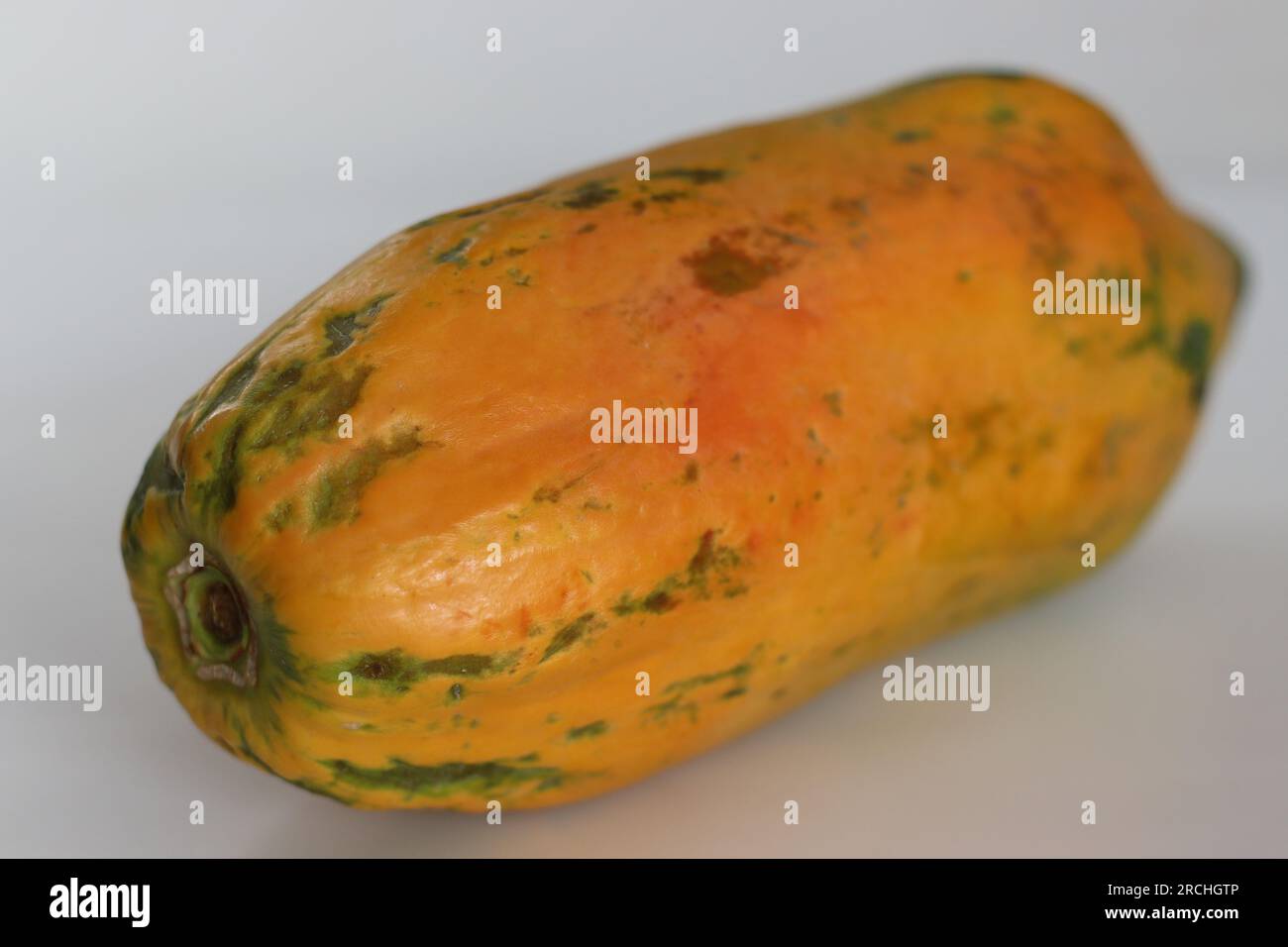 Reif und verzehrfertig. Lange reife Papaya mit orangisch-gelber Haut und weich zu berühren. Aufnahme auf weißem Hintergrund Stockfoto