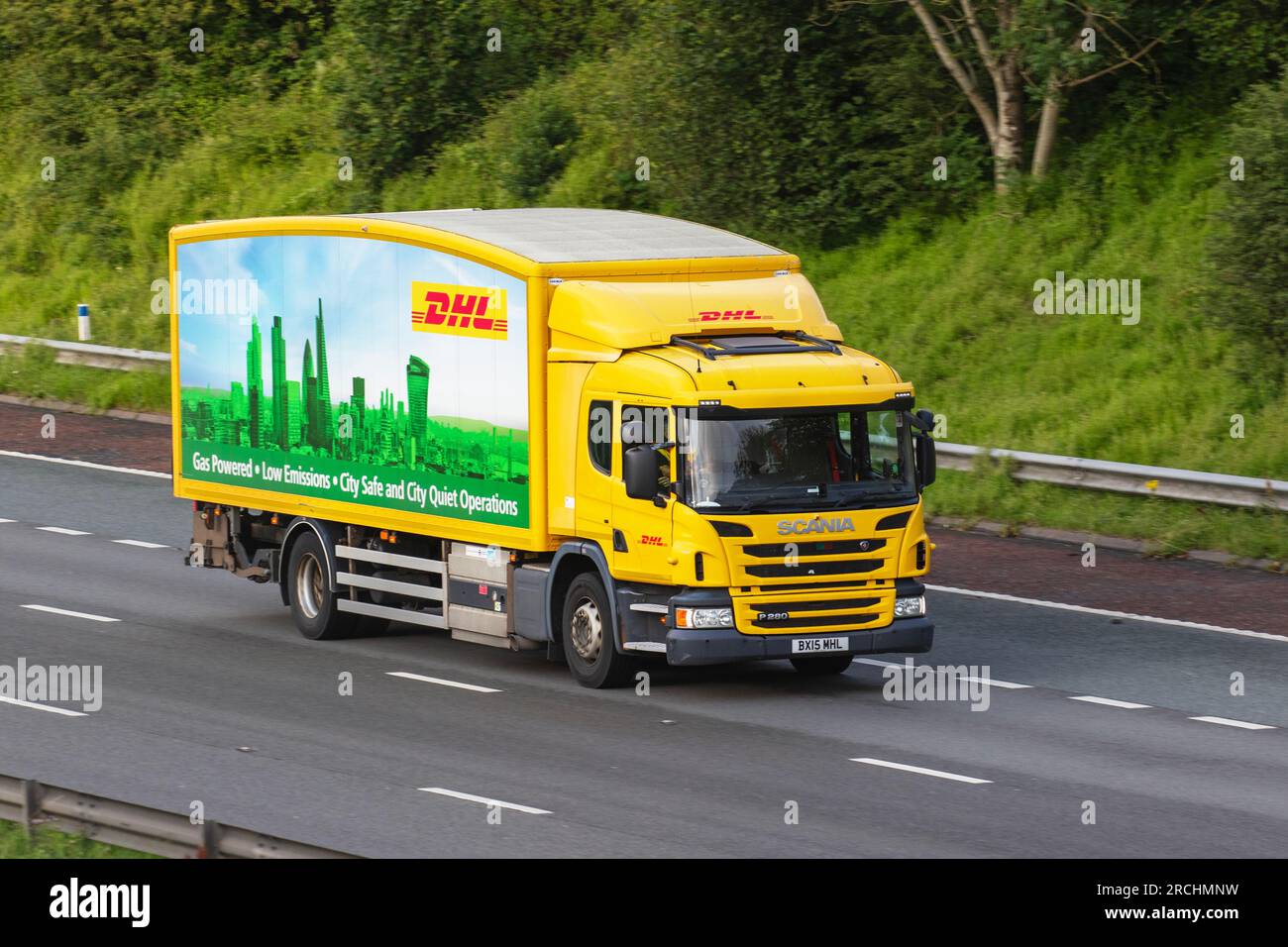 Gasbetriebener, emissionsarmer, City Safe DHL-Liefermann mit gelbem 2023 SCANIA P280, zweiachsiger Lkw, Fahrt auf der Autobahn M6 im Großraum Manchester, Großbritannien Stockfoto