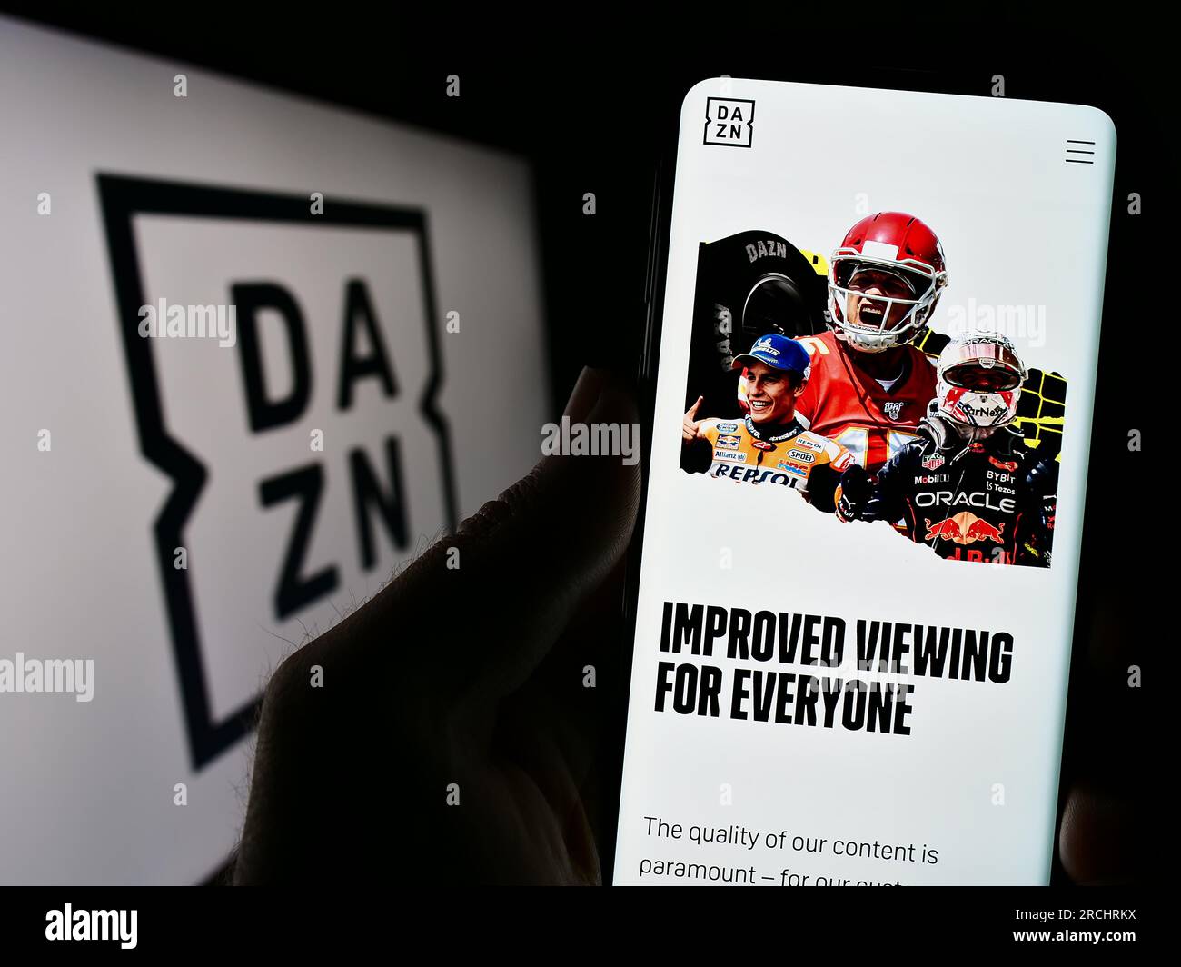 Person, die ein Mobiltelefon mit einer Webseite des britischen Sportmedienunternehmens DAZN Group Limited auf dem Bildschirm mit Logo hält. Konzentrieren Sie sich auf die Mitte des Telefondisplays. Stockfoto