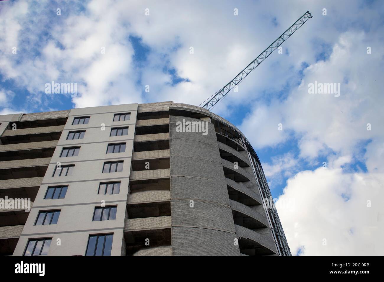 Auf der Baustelle eines Wohnkomplexes wird derzeit ein neues Wohnhaus gebaut. Hintergrund der Baustelle mit Kran an Stockfoto