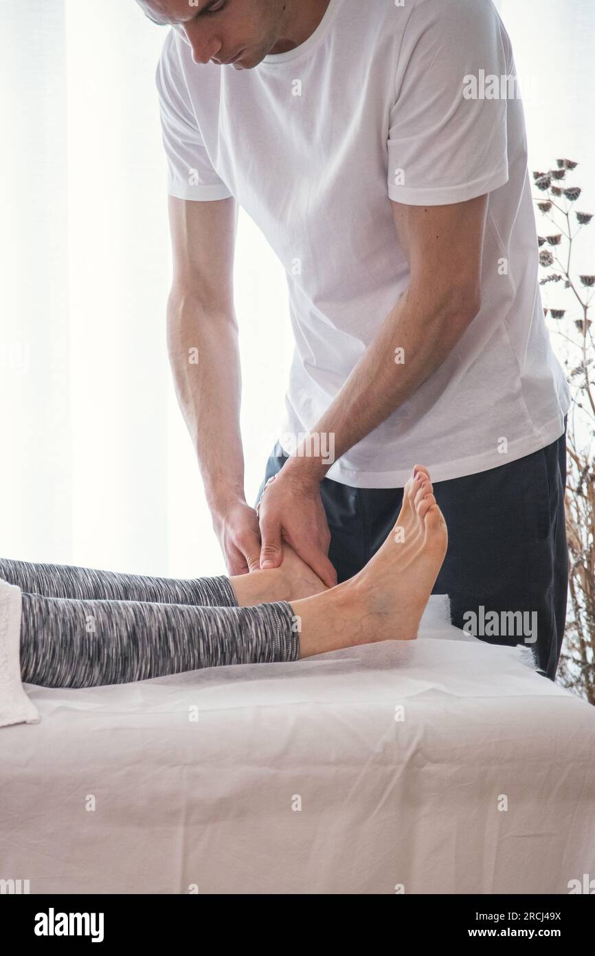Eine Frau, die von einer Therapeutin behandelt wird. Therapeut macht Druck- und Massageübungen durch die Füße, um die allgemeine Gesundheit des Patienten zu verbessern. Stockfoto