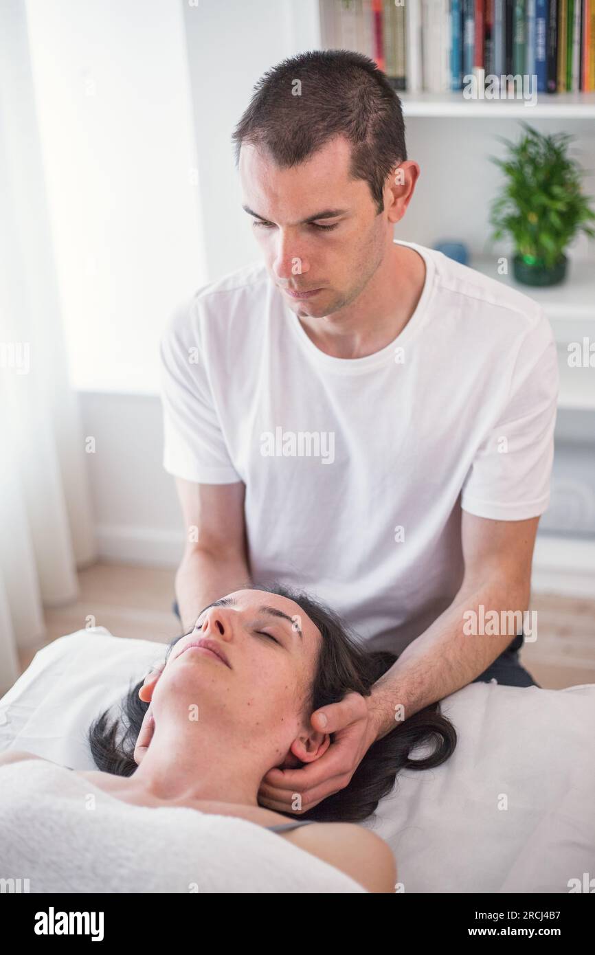 Therapeut, die eine lokale Massage im Schädelbereich unter Anwendung von kleinem, sanftem Druck durchführt. Die kraniosakrale Therapie. Stockfoto