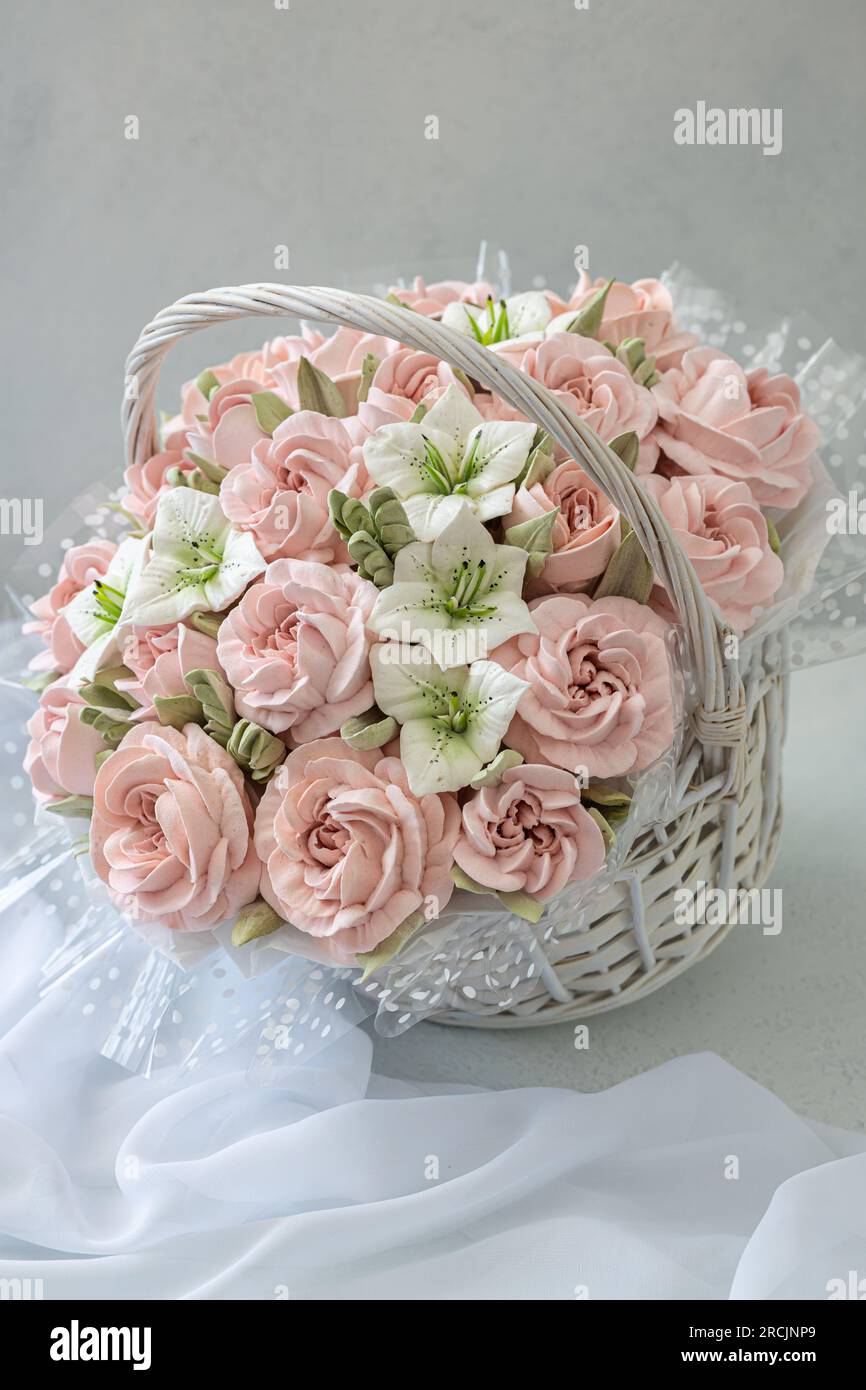 Zephyr-Blumenstrauß in einem Weidenkorb auf hellem Hintergrund Stockfoto