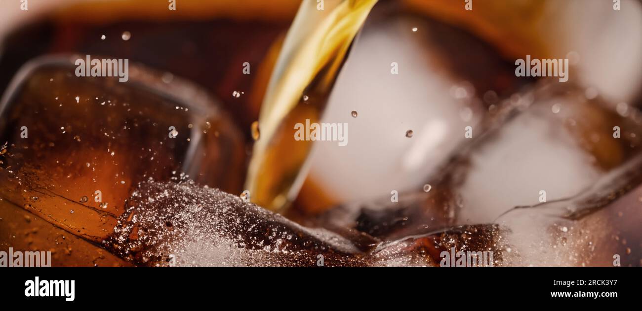 Cola und Eis spritzen, Cola Limo und Eis spritzen, sprudeln oder schweben bis an die Oberfläche. Nahaufnahme von Eis in Cola-Wasser. Konsistenz von Karbonat d Stockfoto