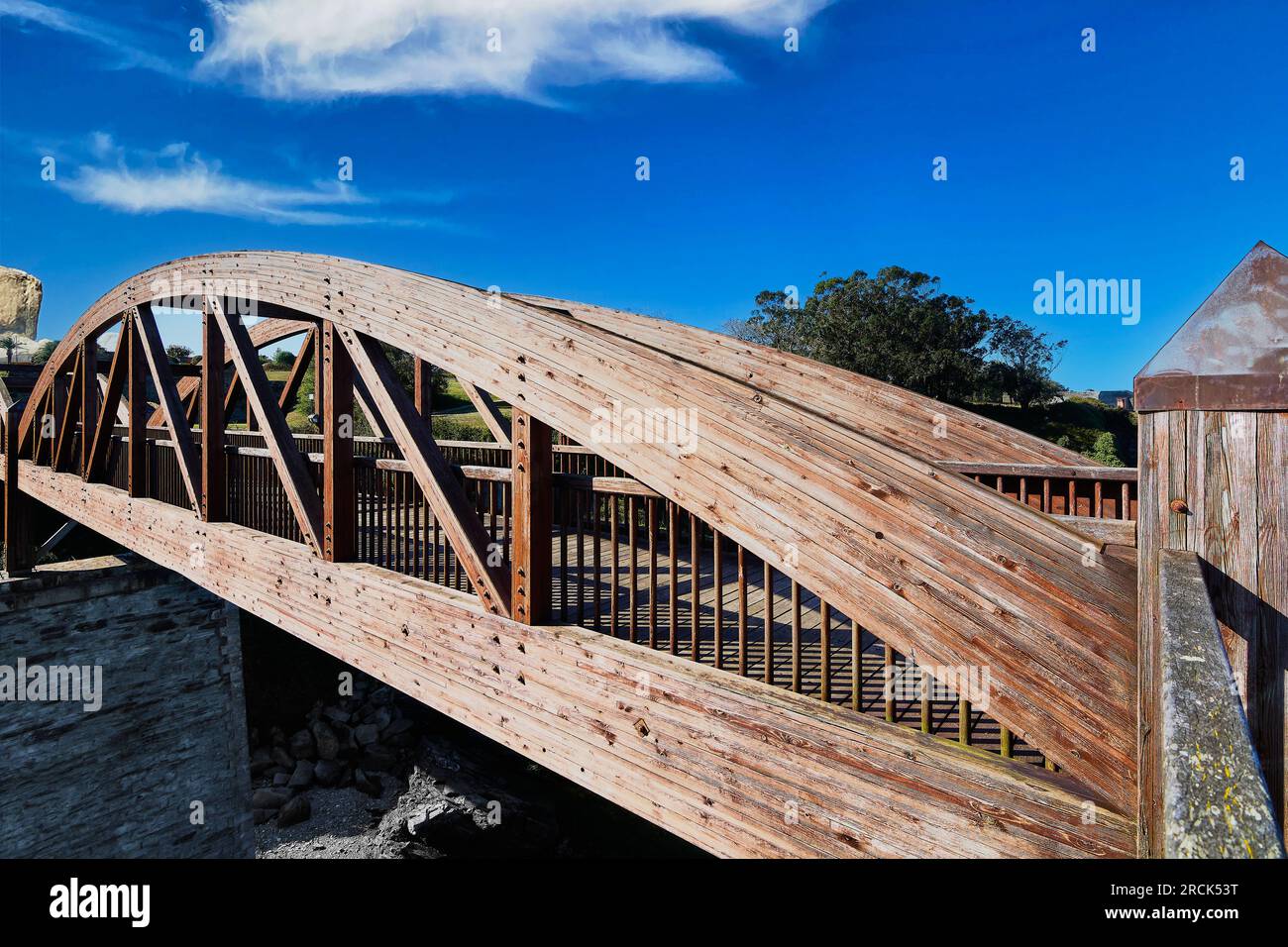 Holzbrücke mit Bögen und brauner Farbe, mit einem wolkigen Himmel auf Steinsäulen in der Ribadeo-Mündung. Stockfoto