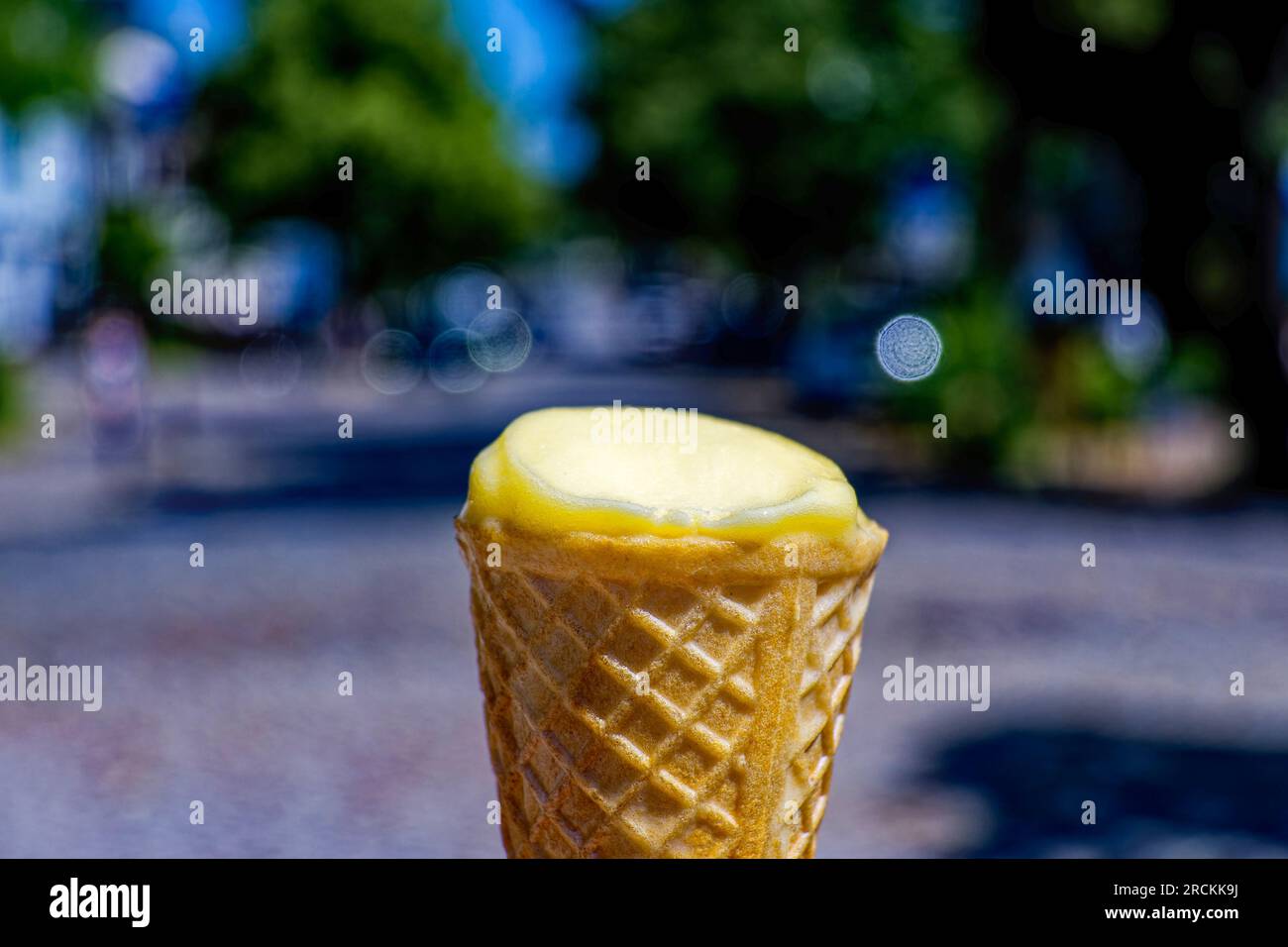 Eiskegel mit einer fast aufgefressenen Eiskugel vor einem verschwommenen Hintergrund. Stockfoto