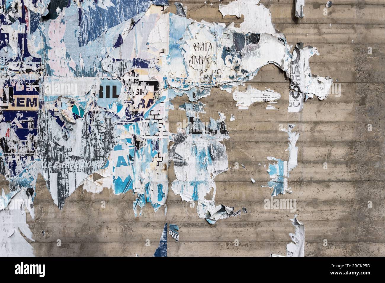 Betonwand mit bunten, zerrissenen Plakaten. Grunge-Hintergrund Stockfoto
