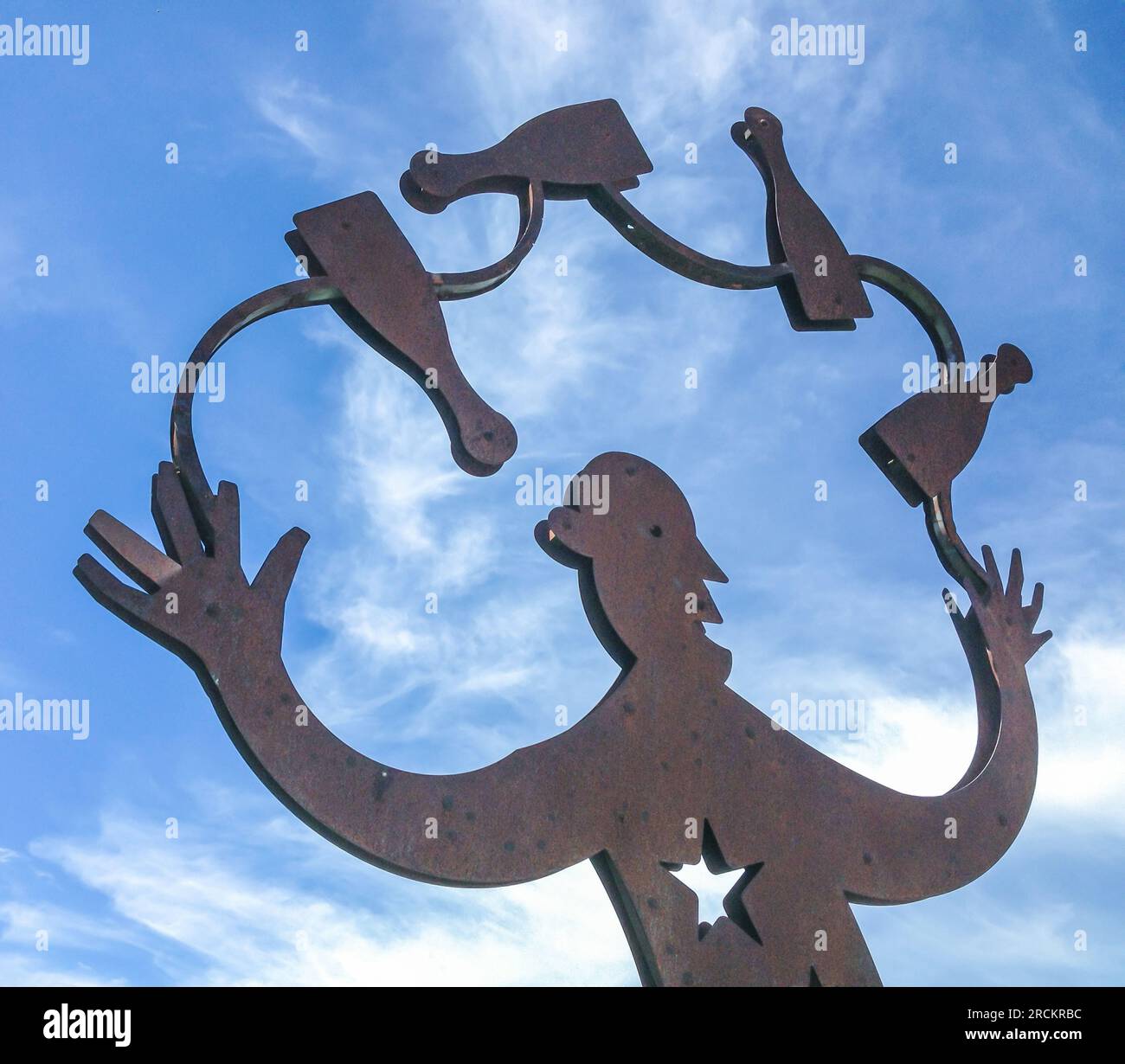 Rostige Metallskulptur in Italien. Jongleur-Mann aus Metallteilen, vor einem blauen Himmel. Stockfoto