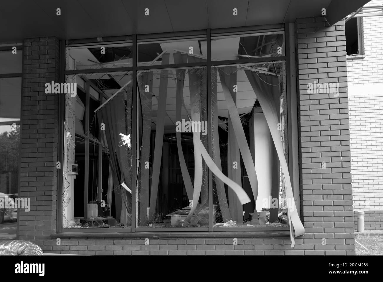 Zerbrochene Fenster des zivilen Bombenbaus. Glasscherben ragen gefährlich in den Fensterrahmen. Krieg zwischen der Ukraine und Russland. Defektes c Stockfoto