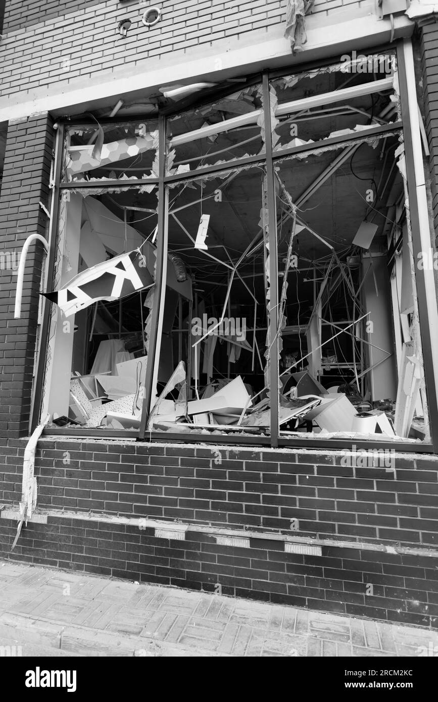 Zerbrochene Fenster des zivilen Bombenbaus. Glasscherben ragen gefährlich in den Fensterrahmen. Krieg zwischen der Ukraine und Russland. Defektes c Stockfoto