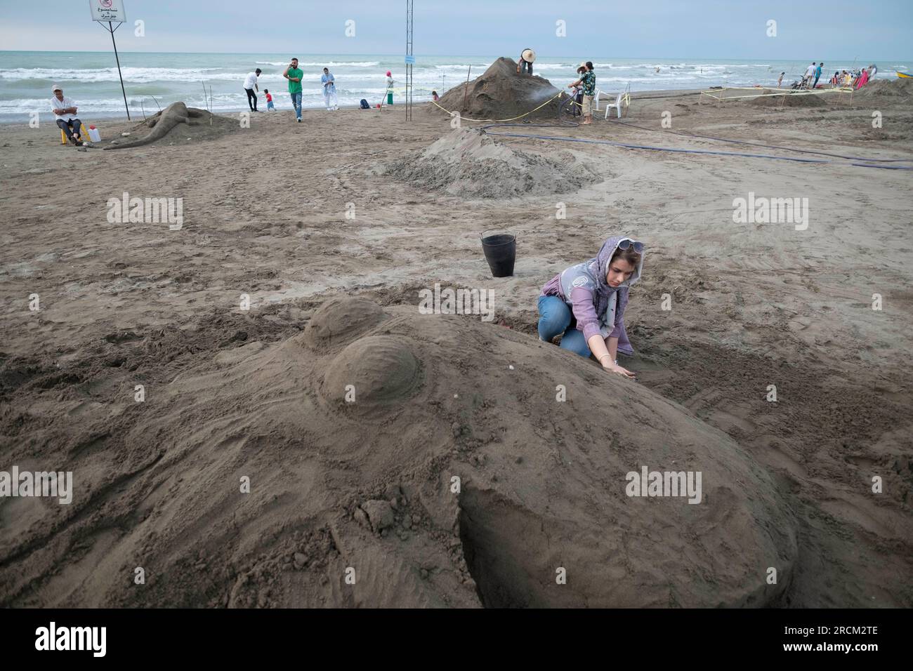 Babolsar, Iran. 13. Juli 2023. Eine iranische Künstlerin arbeitet während des Babolsar National Sand Sculpture Festivals am 13. Juli in Babolsar, Provinz Mazandaran, Nord-Iran, an ihrer Sandskulptur. 2023. Die Stadt veranstaltet ein Sandskulpturenfestival, das die Kreativität und das Talent lokaler Künstler zeigt. Dieses einzigartige Ereignis bietet die Gelegenheit, komplexe Sandskulpturen zu sehen, die von erfahrenen Künstlern geschaffen wurden, die nur Sand und Wasser verwenden und das reiche kulturelle Erbe und die künstlerische Vielfalt des Iran feiern. (Foto: Morteza Nikoubazl/NurPhoto) Kredit: NurPhoto SRL/Alamy Live News Stockfoto