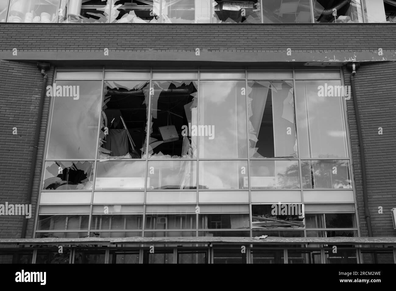 Zerbrochene Fenster des zivilen Bombenbaus. Glasscherben ragen gefährlich in den Fensterrahmen. Krieg zwischen der Ukraine und Russland. Defektes c Stockfoto
