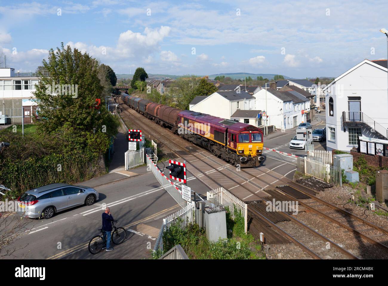 DB Cargo Rail UK-Klasse 66 Lokomotive 66080, die den Bahnübergang in Pencoed mit einem Güterzug aus überdachten Stahlwagen überquert. Stockfoto