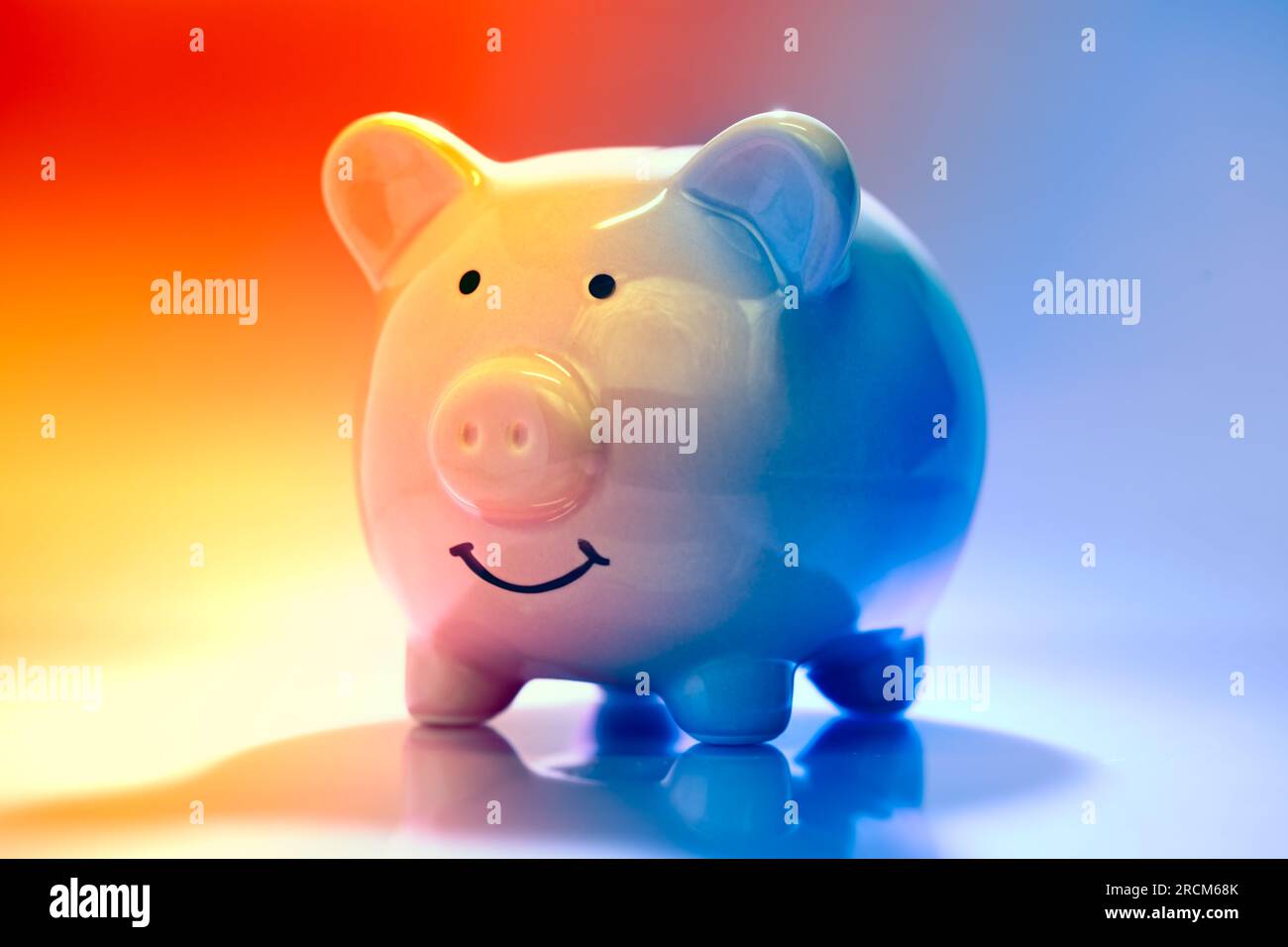 Lächelnde Piggybank auf rotem und blauem Hintergrund. Konzept „Sparen vs. Geld ausgeben“. Stockfoto