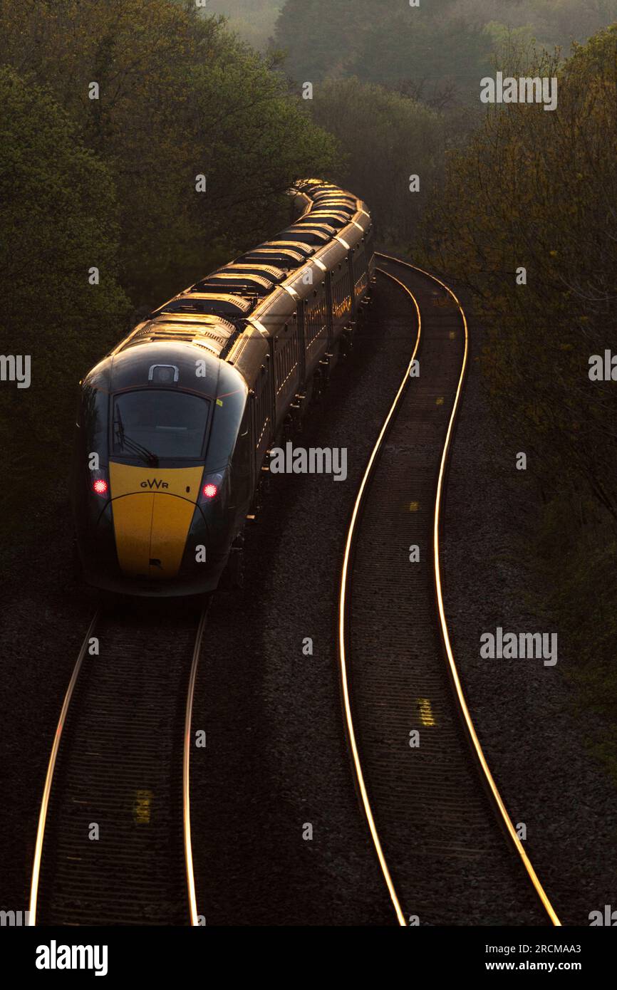 Die erste Great Western Railway Hitachi IET bi - der Moduszug fährt in den Sonnenuntergang auf der Hauptlinie von Süd-Wales bei Llangewydd, die sich um eine Kurve krümmt Stockfoto