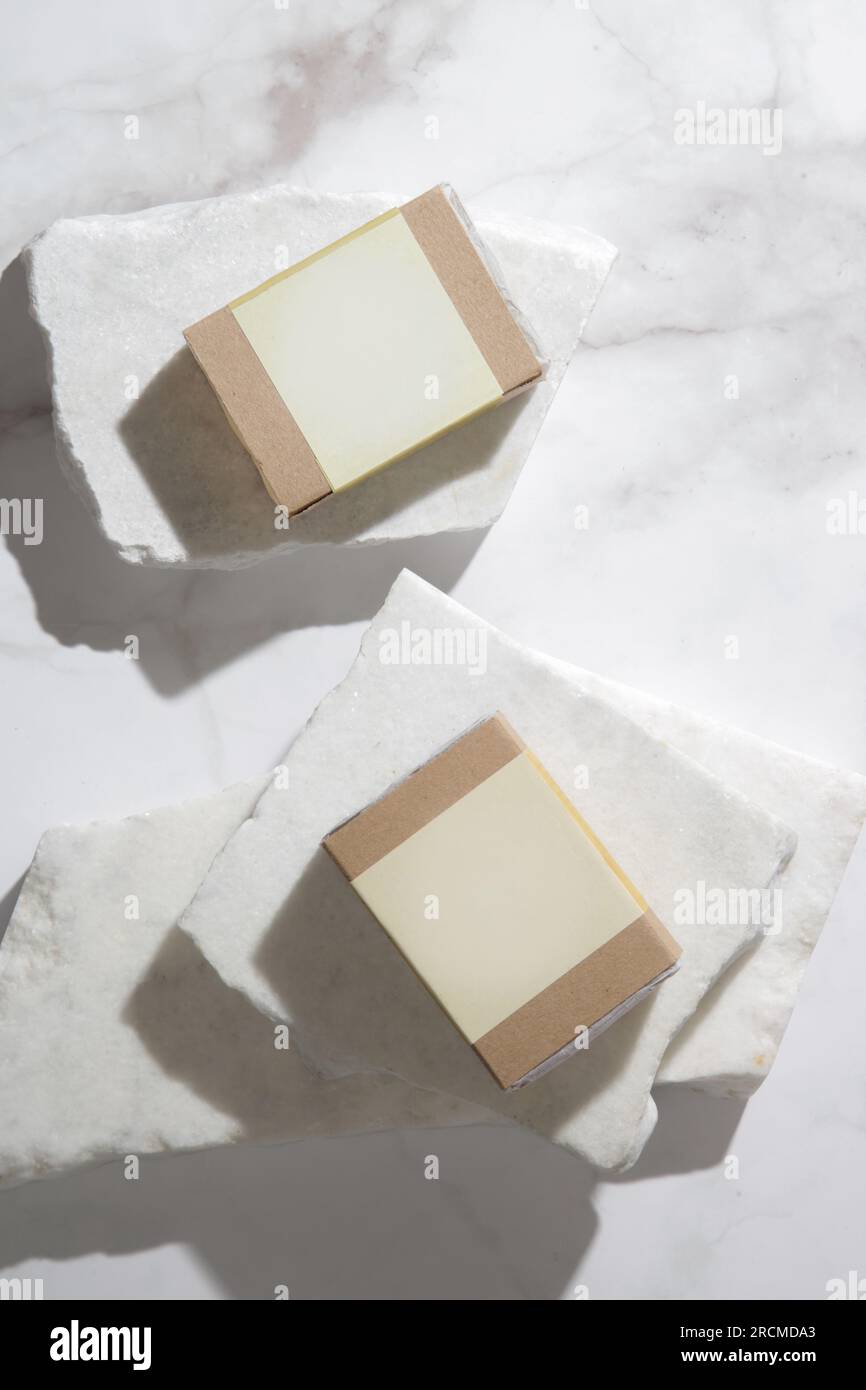 Natürliche Seife für gesunde Haut und Haare in recyceltem Papier mit leerem Etikett, sudio Shot auf marmorfarbenem Hintergrund. Branding und Werbung für Stockfoto