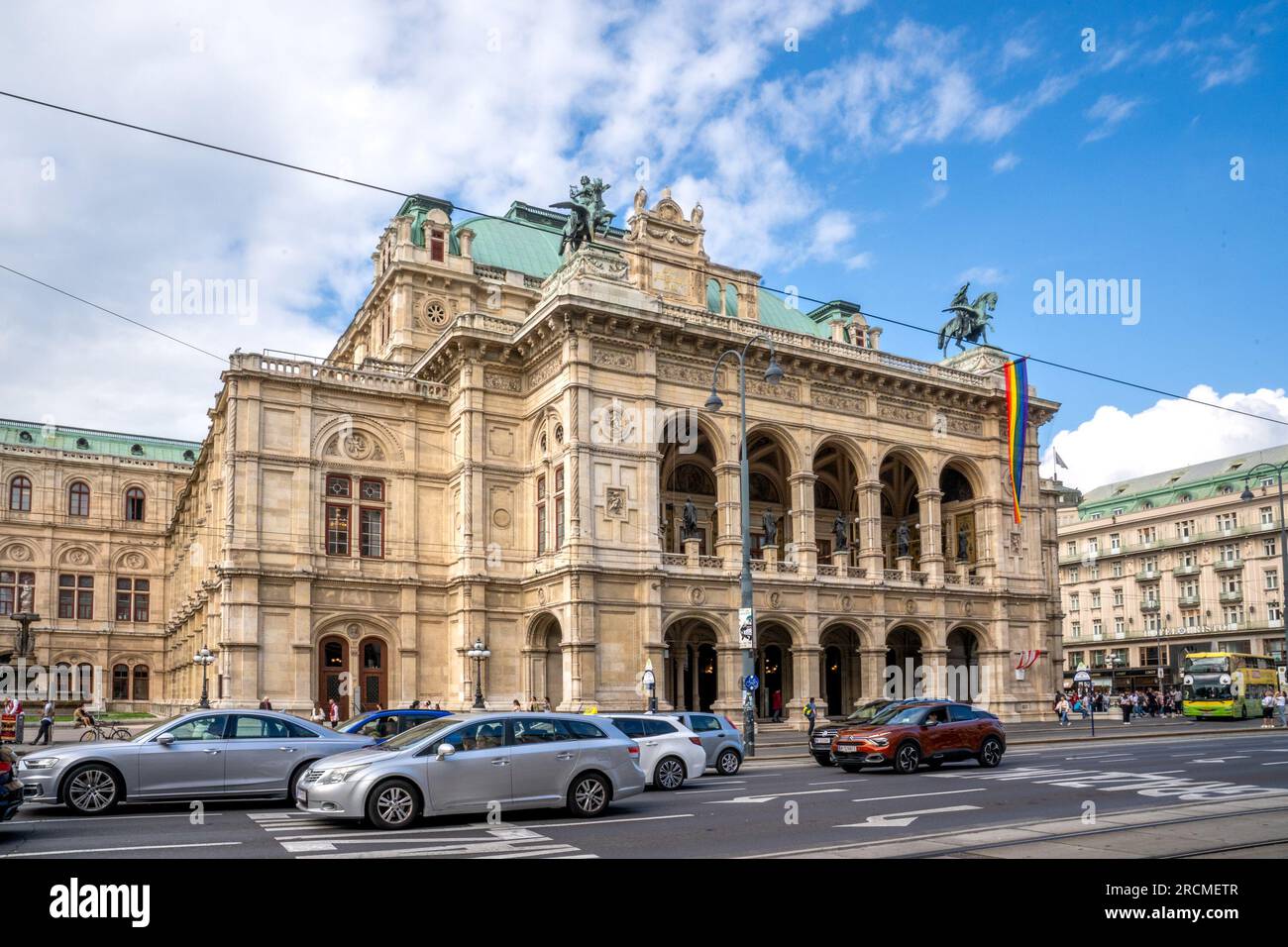 Wien, UM – 9. Juni 2023 Breite Dreiviertelansicht der Touristen, die an der historischen Wiener Operahouse mit 1.709 Sitzplätzen aus der Renaissance-Wiedergeburt vorbeilaufen. Die erste Majo Stockfoto