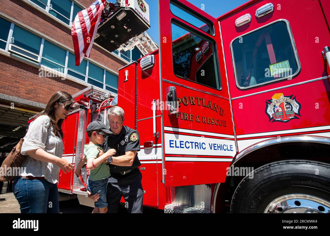 Der fünfjährige Thomas Broekmaat wird von Portland Fire and Rescue PIO Rick Graves unterstützt, um das neue elektrische Feuerwehrauto des Departements zu inspizieren. Stockfoto