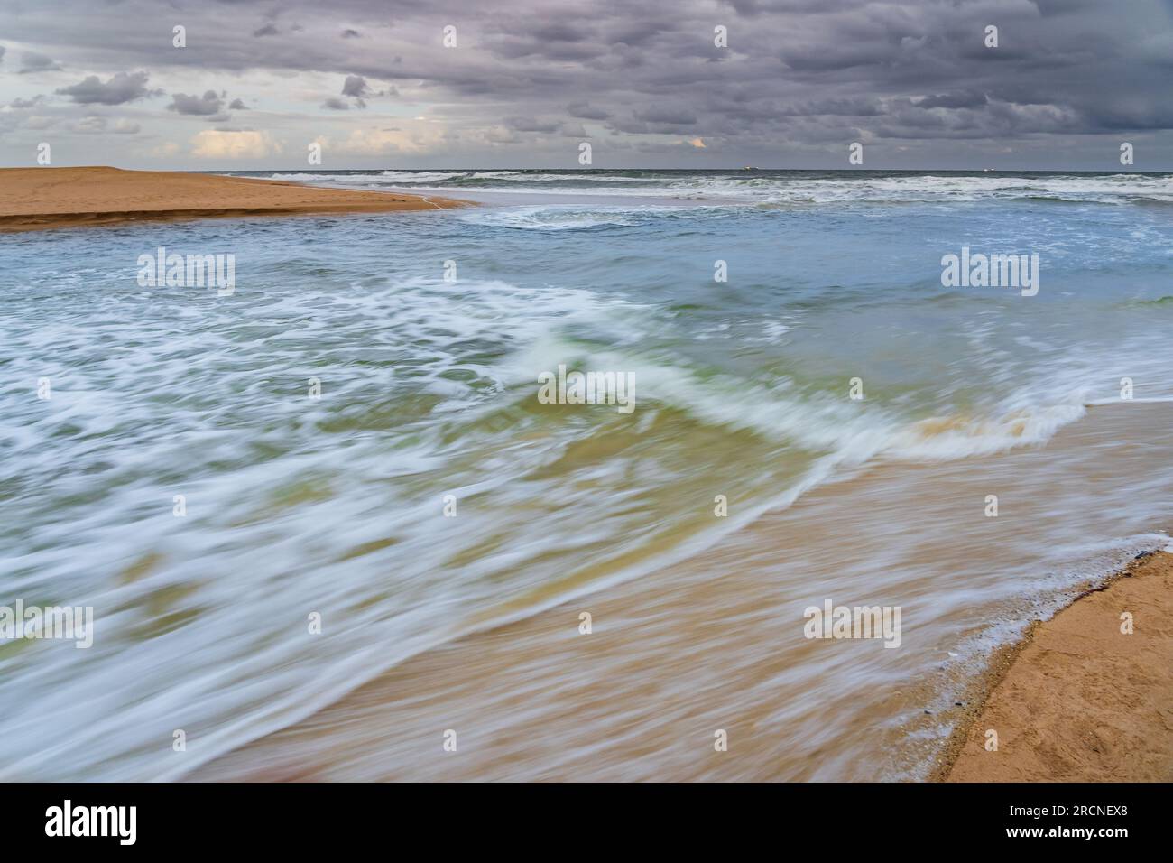 Wasser, das aus einem Küstenfluss zwischen Sandbars an der Sunshine Coast von Currimundi in Queensland, Australien, ins Meer strömt Stockfoto