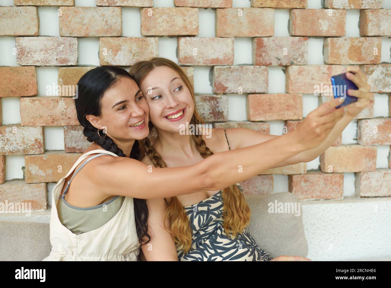 Porträt einer Ukrainerin (brünett) und einer Russin (blond) zusammen mit Zöpfen, die posieren und ein Selfie machen Stockfoto