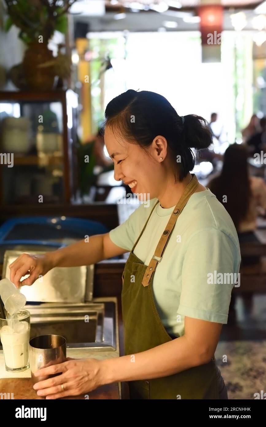 Vietnamesischer Barista verwendet einen Mixer für Kondensmilch in Glasbecher zur Zubereitung von vietnamesischem Kaffee Café Sua Stockfoto