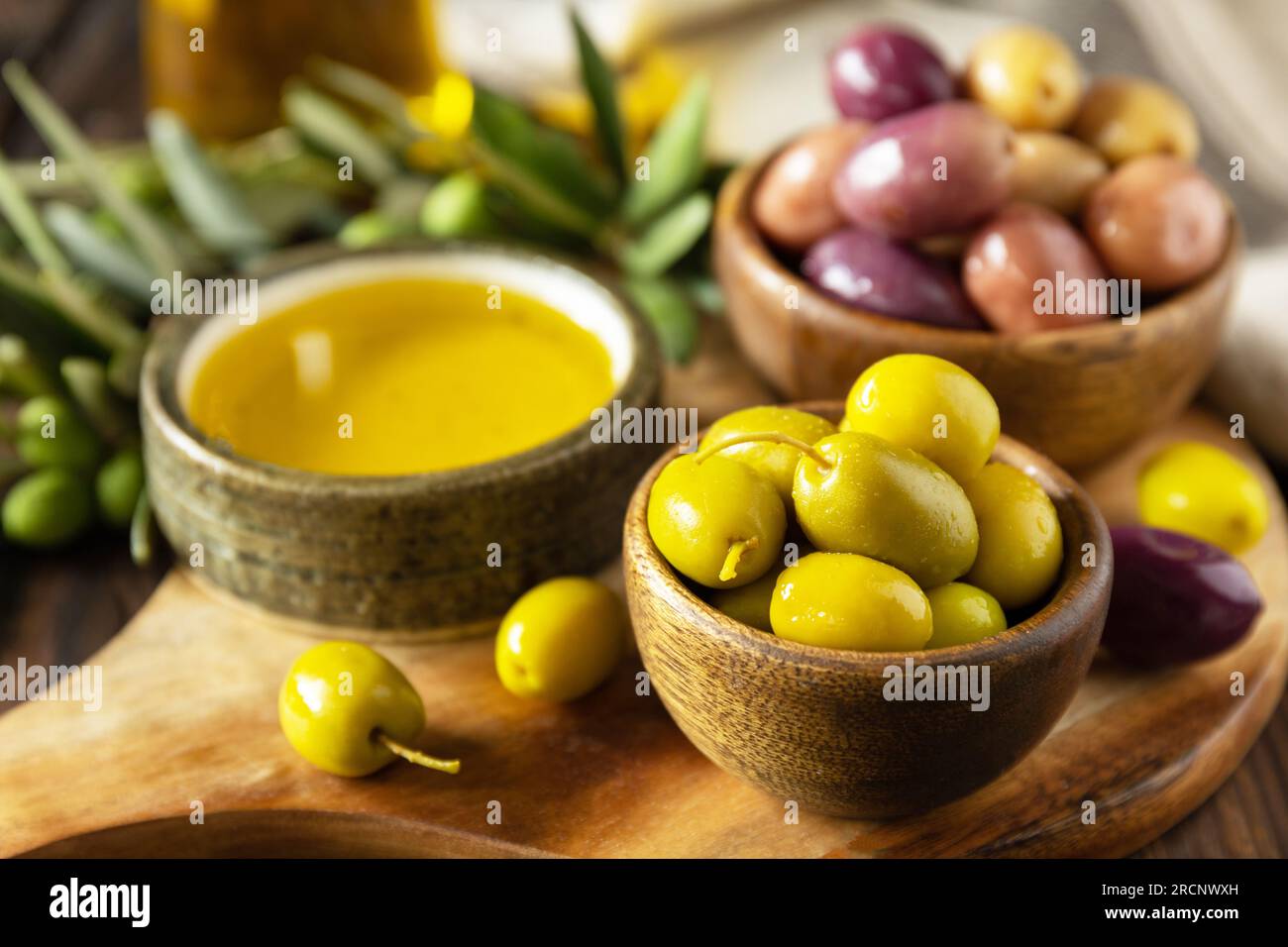 Frisch gepflückte Oliven Beeren in Holzschüsseln und Pressöl auf alten Holzbrettern serviert. Stockfoto