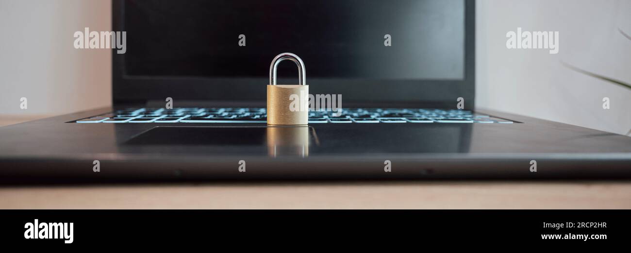 Weitwinkelbild eines goldenen Vorhängeschlosses auf einem offenen Laptop. Konzeptionelles Bild von Cybersicherheit, Datenschutz und Firewall. Stockfoto