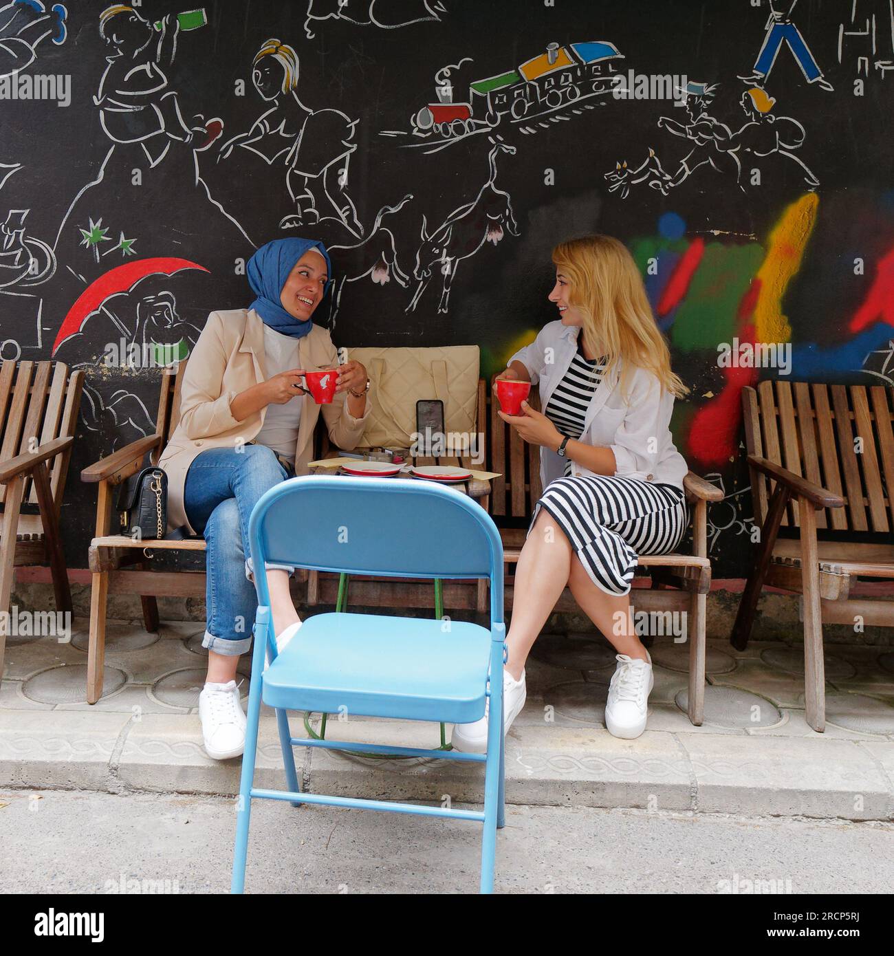 Zwei Freunde unterhalten sich und lächeln bei einem Kaffee in einem Café/Restaurant im Viertel Karakoy in Istanbul, Türkei Stockfoto
