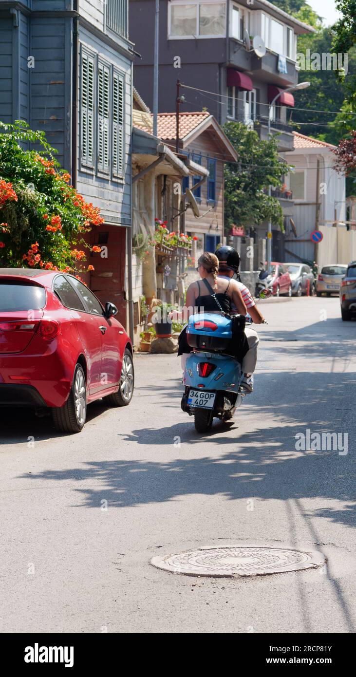 Motorradfahrer mit Sozius auf einer malerischen Straße in Anadolu auf der asiatischen Seite von Istanbul, Türkei. Holzhaus mit Blumen auf der linken Seite Stockfoto