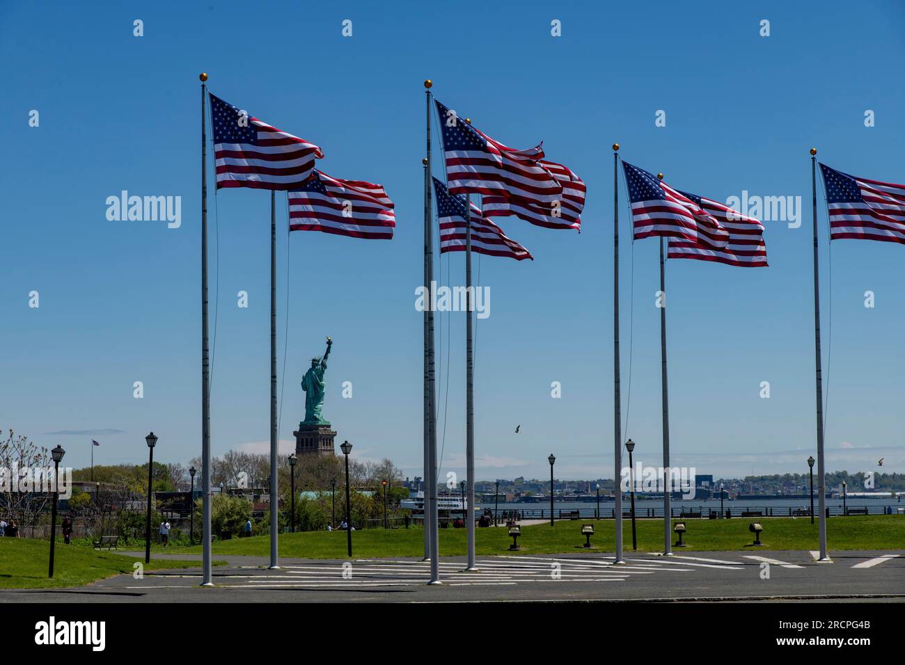 Jersey City, NJ, USA – Mai 2022; Blick über die Flag Plaza im Liberty State Park mit amerikanischen Flaggen im Wind und Blick auf die Freiheitsstatue gegen einen Cl Stockfoto