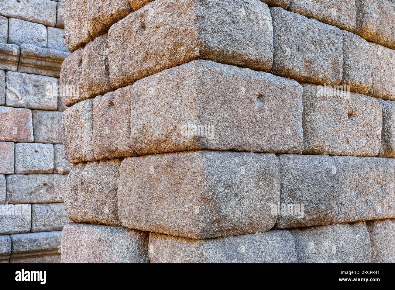 Segovia, Spanien - 11. Februar 2023: Römisches Aquädukt. Nahaufnahme der mittelalterlichen Steine, die Teil der Stütze oder Basis sind. Sie haben kleine Bohrungen, die für f verwendet werden Stockfoto