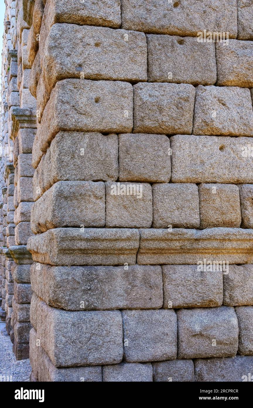 Segovia, Spanien - 11. Februar 2023: Römisches Aquädukt. Nahaufnahme der mittelalterlichen Steine, die Teil der Stütze oder Basis sind. Sie haben kleine Bohrungen, die für f verwendet werden Stockfoto