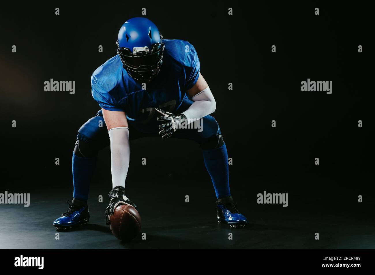 Ein amerikanischer Fußballspieler ist bereit, das Spiel auf schwarzem Hintergrund zu starten. Stockfoto