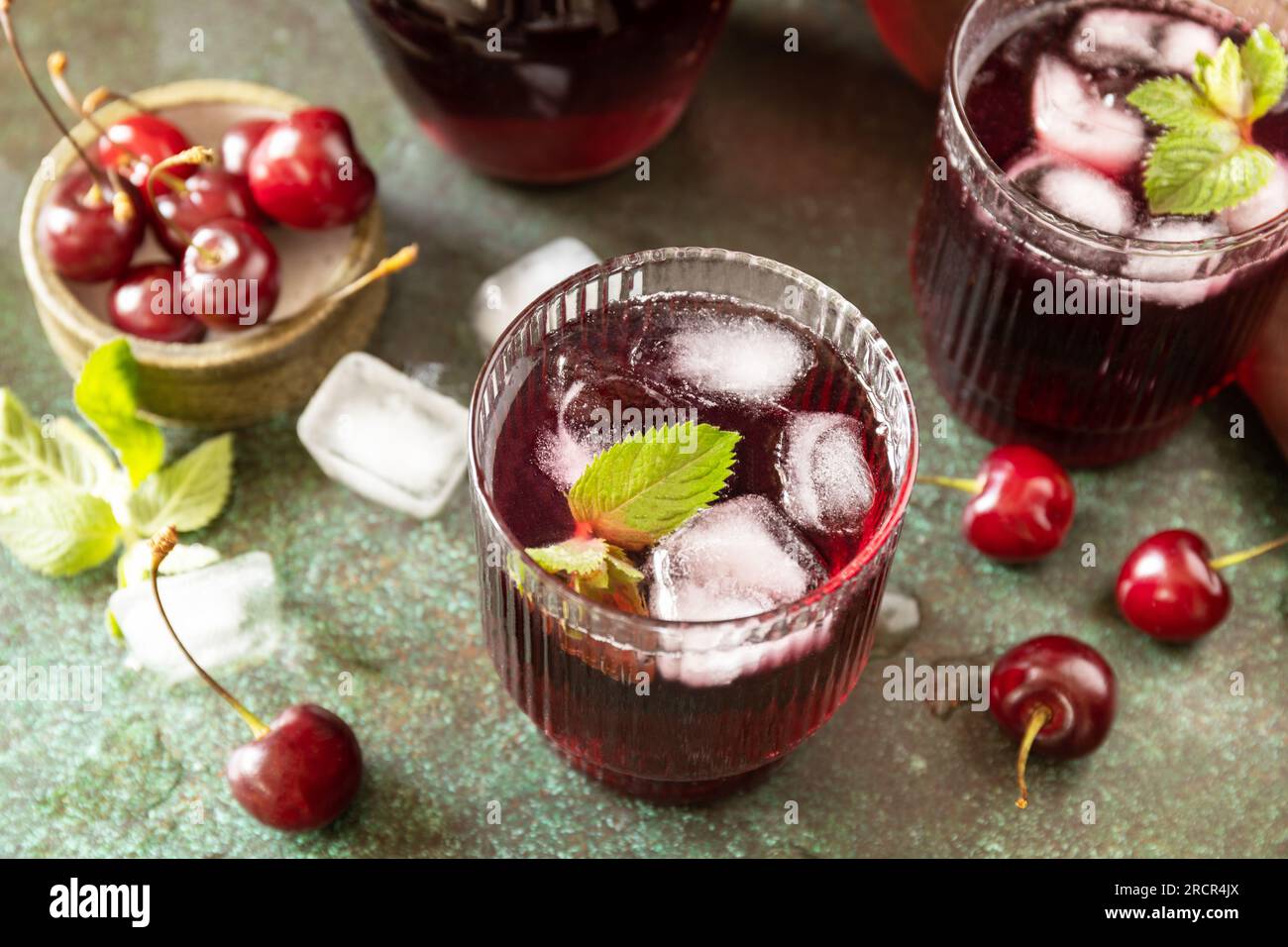 Kalte erfrischende Kirschcola in einem Glas mit Eis auf Steinhintergrund, Sommersaft. Stockfoto