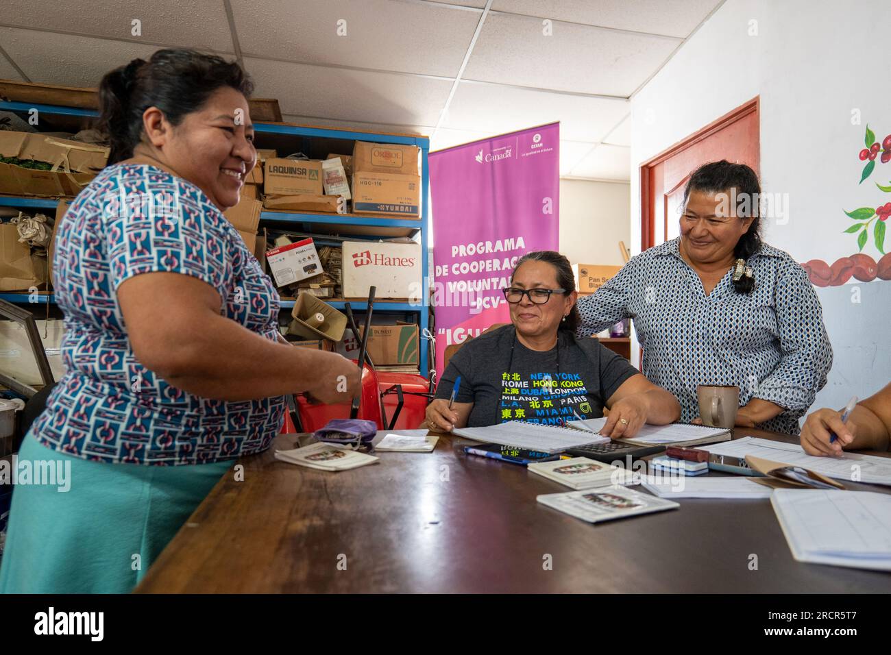 El Espino, La Libertad, El Salvador - Oktober 11 2022: Frauen, die sich zusammentun, um andere an einem Tisch zu bezahlen und Geld während eines Community Saving Group Meetin zu zählen Stockfoto