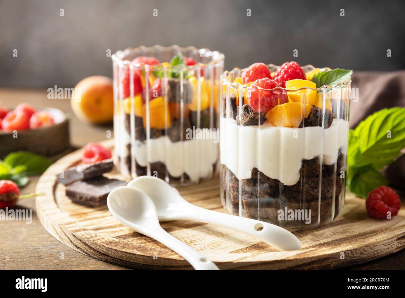 Sommerliche gesunde Ernährung Frühstück, Snackkonzept. Ein paar Schokokekse mit Joghurt und frischen Beeren und Obst. Zwei portionierte Glasparfafait des Stockfoto