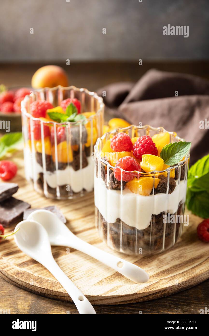 Ein paar Schokokekse mit Joghurt und frischen Beeren und Obst. Zwei Portionen Parfafait-Dessert aus Glas. Sommer gesunde Ernährung Frühstück, Snack Kontra Stockfoto