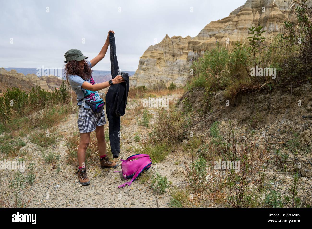 Palca, La Paz, Bolivien - 7 2022. August: Junge indigene Frau zieht ihre Weste bei einem Spaziergang in den Bergen des Valle de Las Animas (Spirits' Valley) Stockfoto