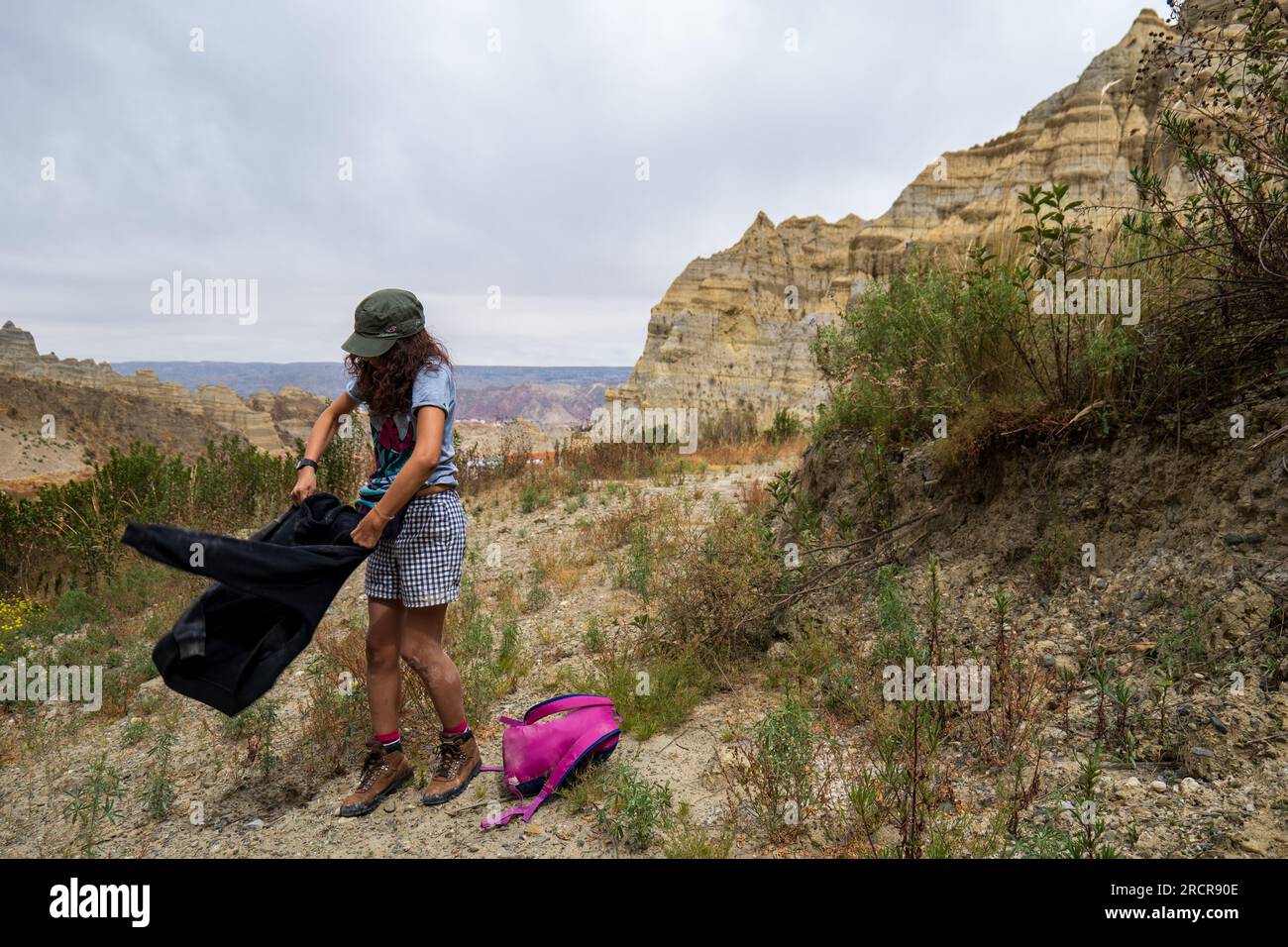 Palca, La Paz, Bolivien - 7 2022. August: Junge indigene Frau schüttelt ihre Weste bei einem Spaziergang in den Bergen des Valle de Las Animas (Spirits' Valley Stockfoto