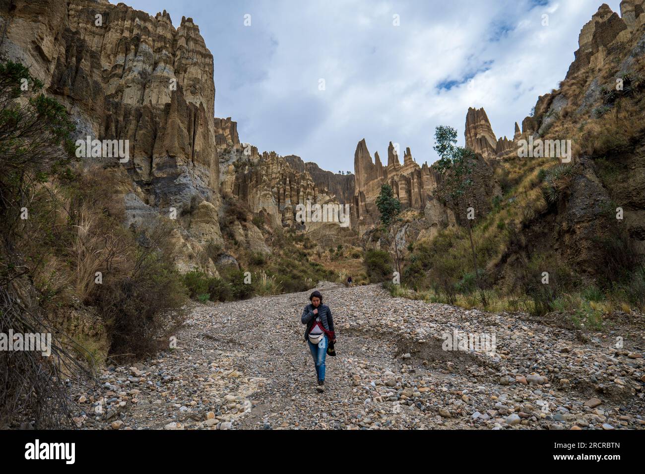 Palca, La Paz Bolivien - August 7 2022: Junge indigene Frau geht allein auf einem trockenen Flussbett in den Bergen von Valle de Las Animas (Spirits' Stockfoto