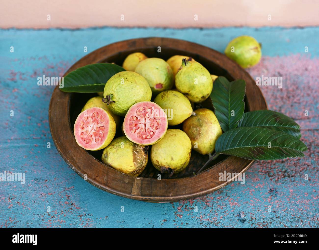 Reife Guaven auf einem Holzteller im Garten. Tropische organische Früchte, gesunde Ernährung oder Diätkonzept (Psidium guajava). Selektiver Fokus. Stockfoto