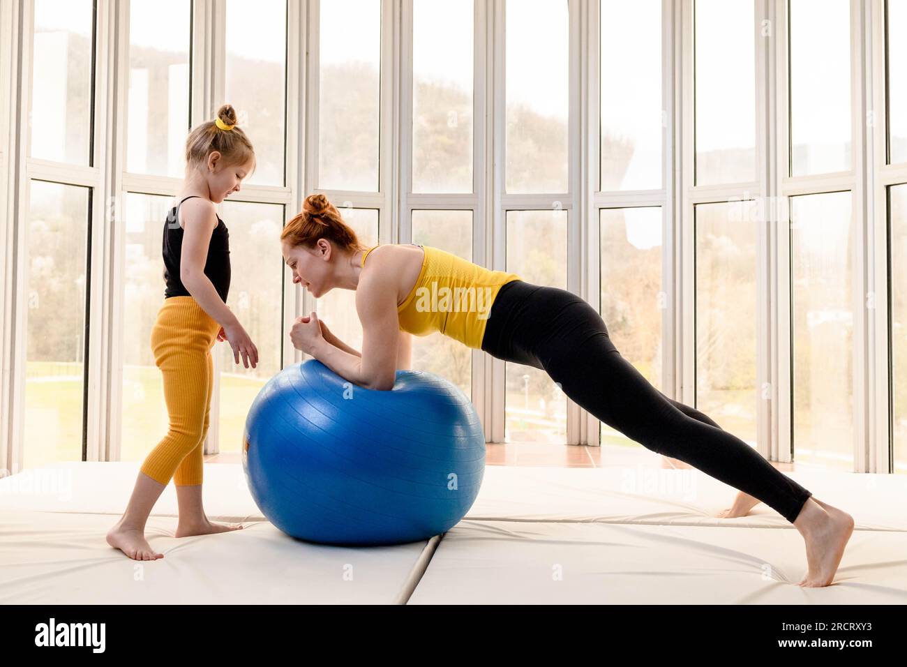 Junge fit Mutter und ihre Tochter Spaß mit Fitness-Ball in einem Fitnessstudio Stockfoto