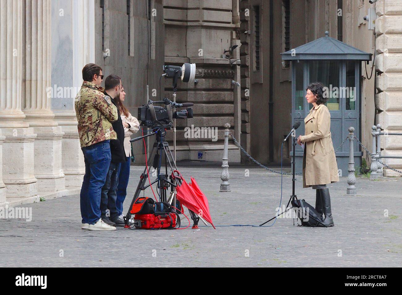 Ein italienisches TV-Team beginnt mit dem Filmen eines Nachrichtenberichts vor der Piazza Colonna, Rom, zwischen Regenschauern, April 2023. Stockfoto