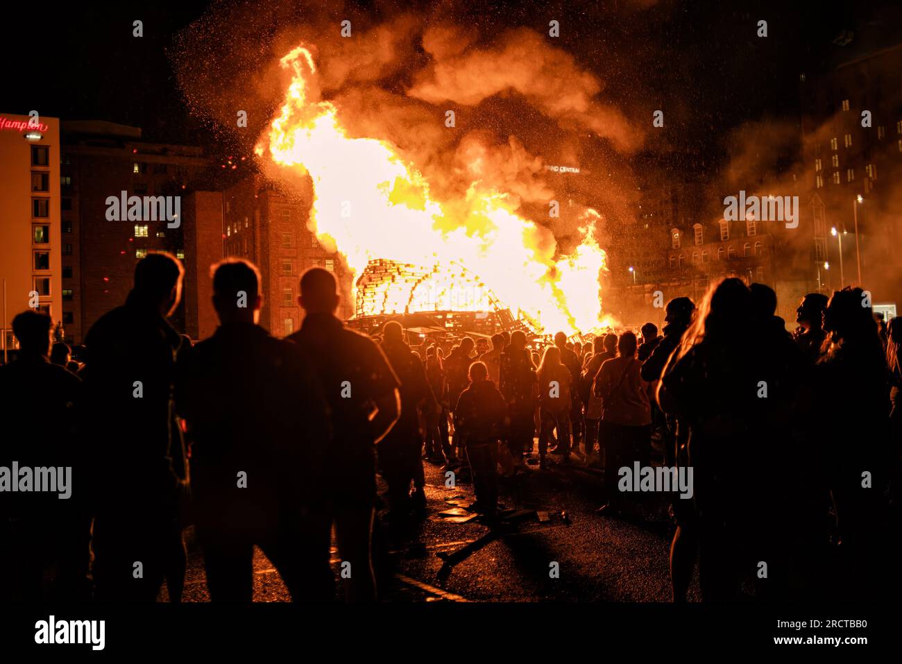 Belfast, Großbritannien. 14. Juli 2023. Protestanten und Loyalisten versammeln sich in der Sandy Row, um die 11. Nacht zu feiern, während sie ein großes Lagerfeuer in Flammen beobachten. Um die Schlacht von Boyne zu feiern, werden Lagerfeuer in verschiedenen protestantischen Vierteln in Belfast gebaut, und Straßen und Häuser sind mit Union Jacks geschmückt. Die Lagerfeuer werden in der Nacht vor den Paraden zum 12. Juli angezündet. (Foto: Natalia Campos/SOPA Images/Sipa USA) Guthaben: SIPA USA/Alamy Live News Stockfoto